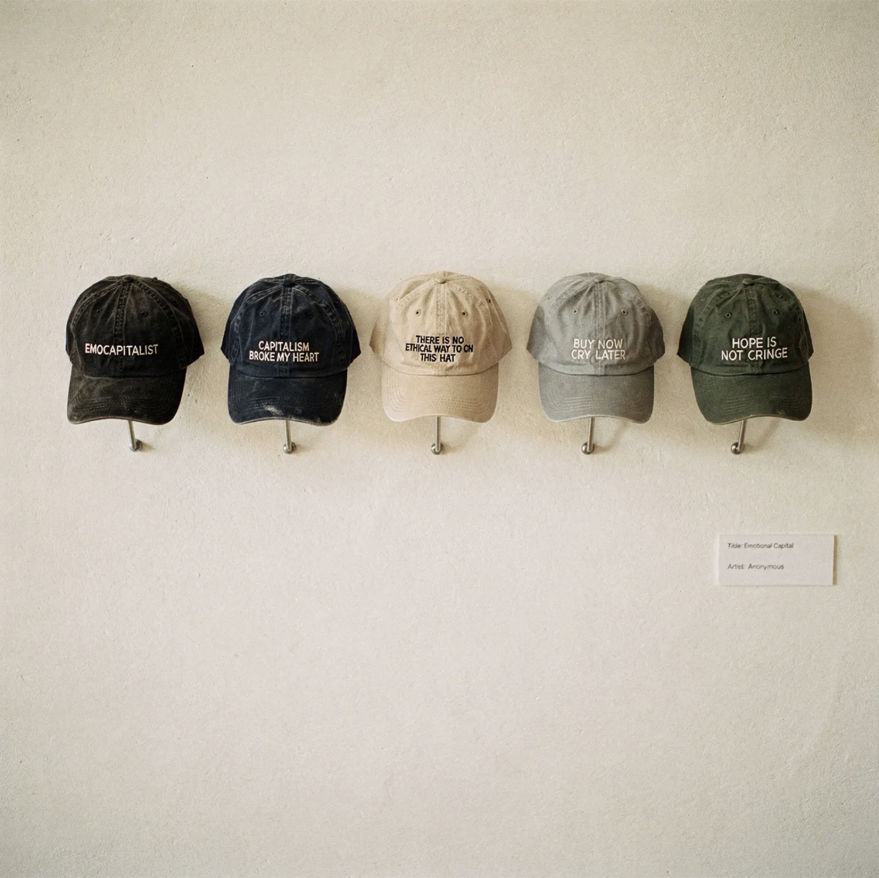 Five EMOCAPITALIST embroidered caps installed on a gallery wall